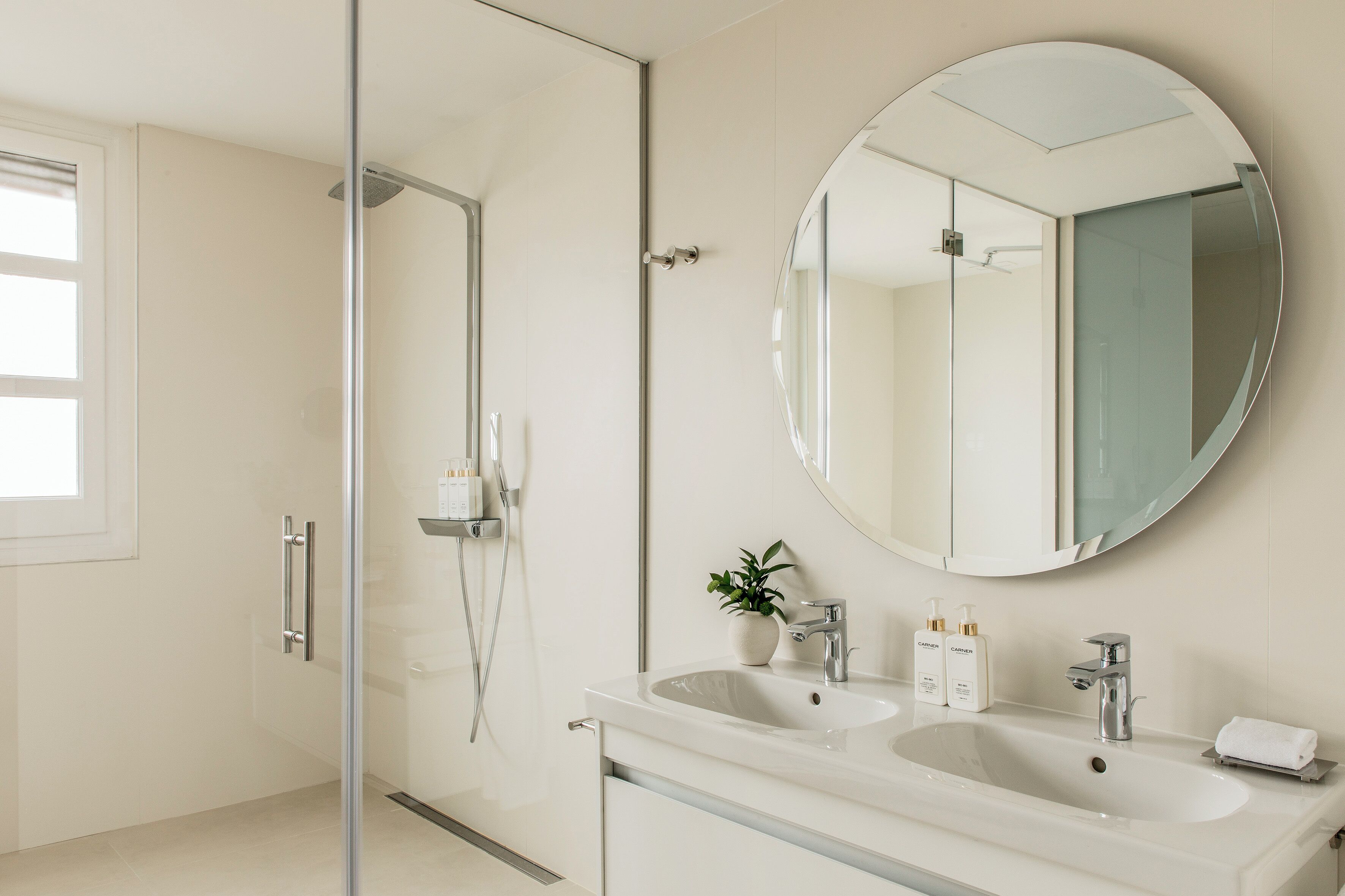 Un bagno moderno con cabina doccia in vetro, mobile lavabo doppio e uno specchio grande.