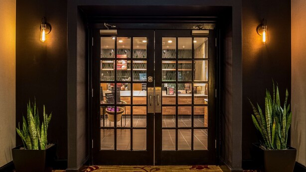 A Starbucks entrance with a dark facade, a green logo, and a patterned carpet leading to the entrance. - Hilton Fort Wayne at the Grand Wayne Convention Center (Fort Wayne)