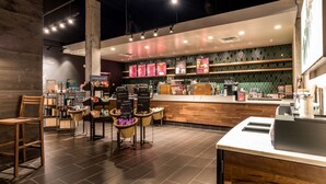 A modern cafe interior with a wooden counter, menu boards, and seating area. - Hilton Fort Wayne at the Grand Wayne Convention Center (Fort Wayne)