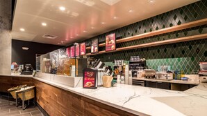 A modern coffee shop interior with a marble counter, wooden accents, and menu boards. - Hilton Fort Wayne at the Grand Wayne Convention Center (Fort Wayne)