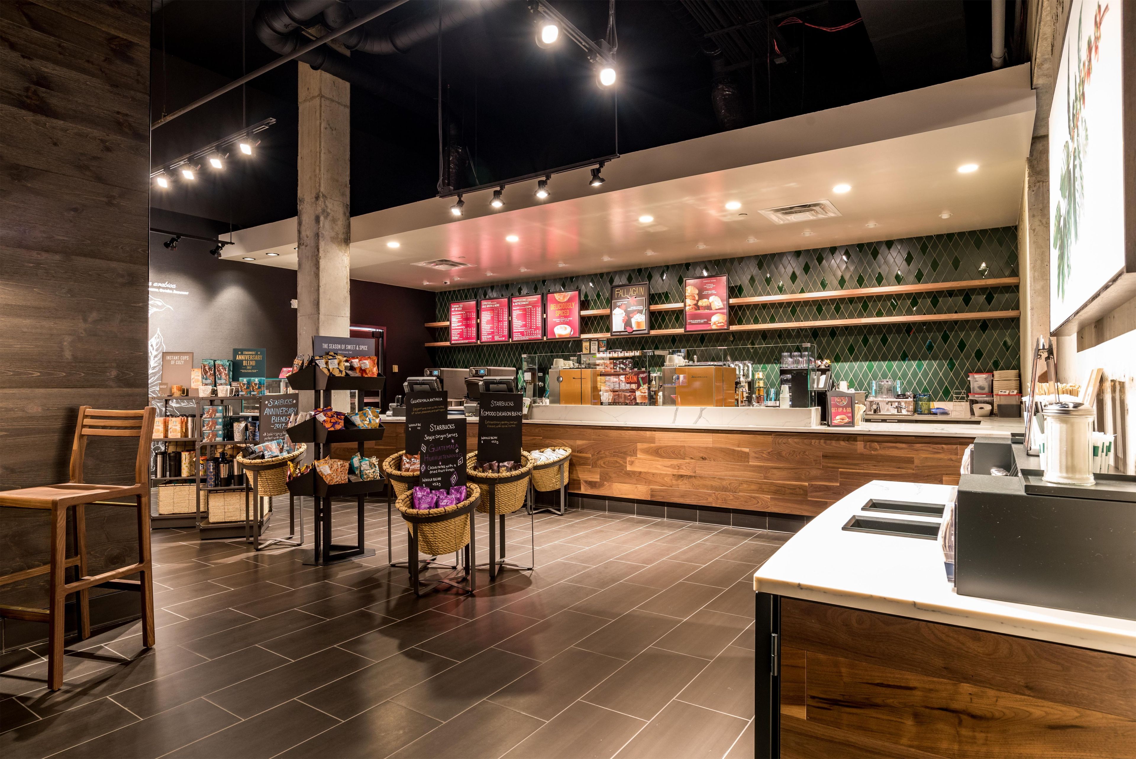 Interior de uma cafeteria com balcão, área de estar e diversos produtos de café expostos.