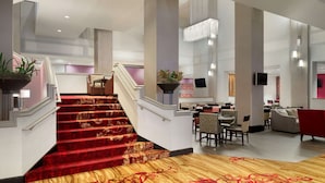 A hotel lobby with a grand staircase, seating area, and a chandelier. - Hilton Fort Wayne at the Grand Wayne Convention Center (Fort Wayne)