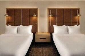 A hotel room with two beds, each with a headboard and bedside lamps. There is a wooden nightstand between the beds with a drawer. - Hilton Fort Wayne at the Grand Wayne Convention Center (Fort Wayne)