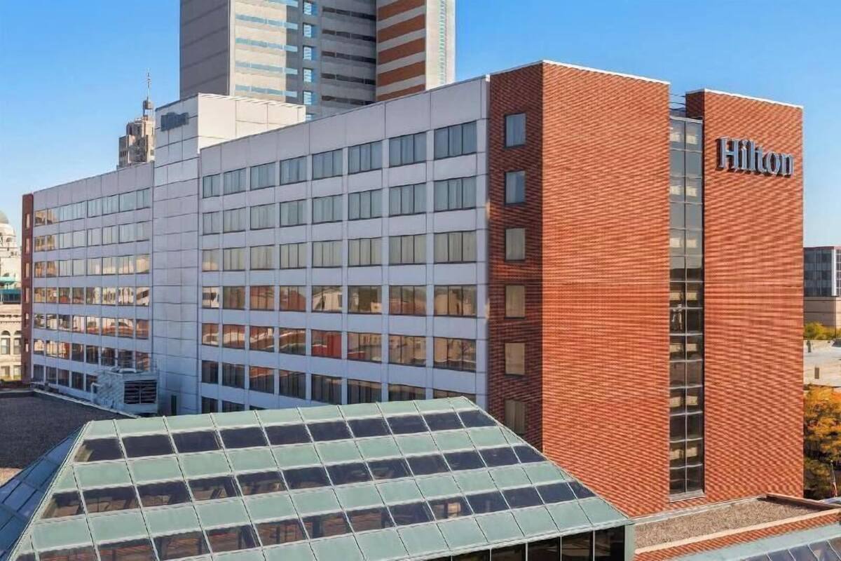 A modern hotel with a prominent red-brick facade, large windows, and a flat roof with solar panels.
