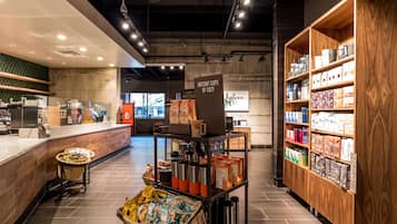 Un interior moderno de cafetería con mostrador, zona de estar y estanterías llenas de productos de café.