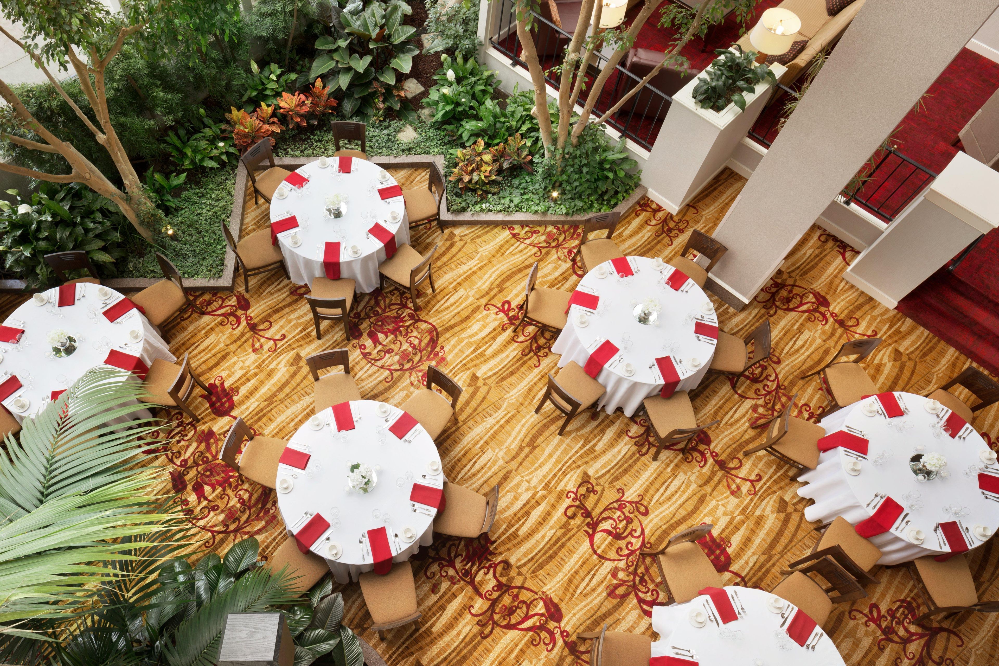 Ein Hotel-Speisesaal mit mehreren runden Tischen, Stühlen und einem Teppichboden.