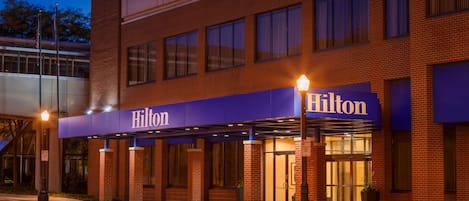A Hilton hotel with a brick facade, large windows, and a covered entrance area.