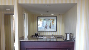 A hotel room with a dark wooden desk, a framed artwork above the desk, and a striped wall. - Hilton Fort Wayne at the Grand Wayne Convention Center (Fort Wayne)