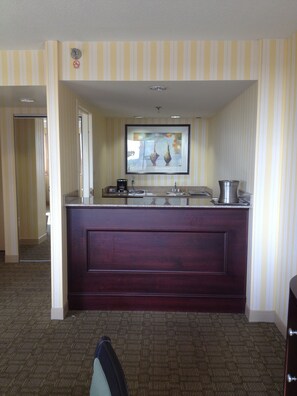A hotel room with a dark wooden desk, a framed artwork above the desk, and a striped wall. - Hilton Fort Wayne at the Grand Wayne Convention Center (Fort Wayne)