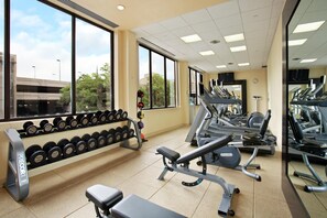 A gym with exercise equipment, a bench, and dumbbells.