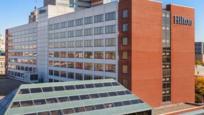 A modern hotel building with a prominent Hilton sign, large windows, and a green roof. - Hilton Fort Wayne at the Grand Wayne Convention Center (Fort Wayne)