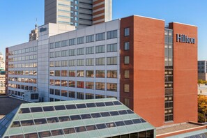 A modern hotel building with a prominent Hilton sign, large windows, and a green roof. - Hilton Fort Wayne at the Grand Wayne Convention Center (Fort Wayne)