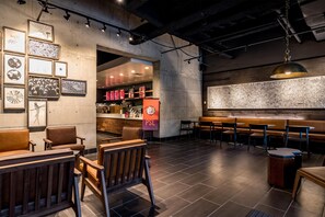 A cafe interior with a bar area, seating, and wall art. - Hilton Fort Wayne at the Grand Wayne Convention Center (Fort Wayne)