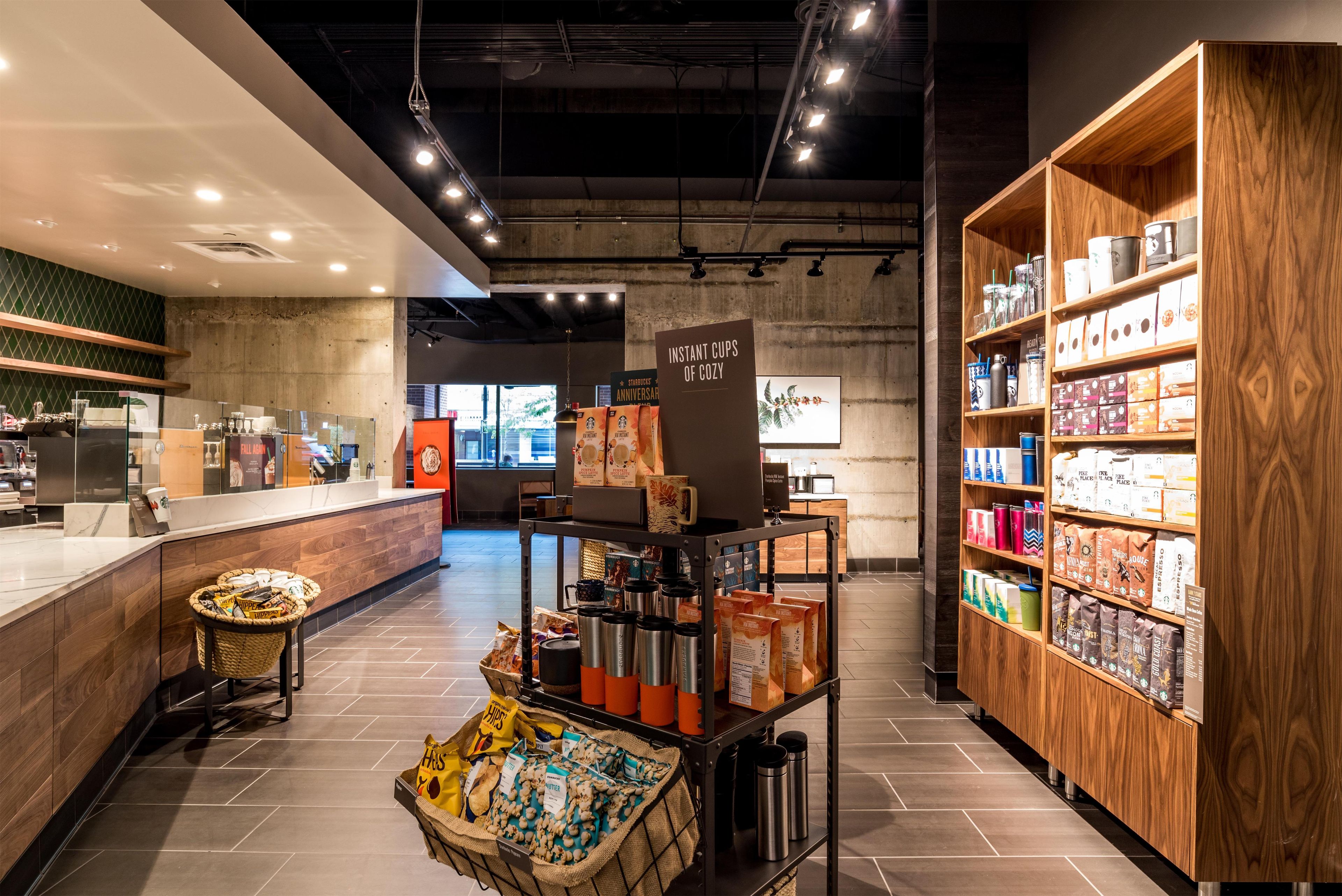 Interior moderno de uma cafeteria, com balcão, área de estar e prateleiras repletas de produtos de café.