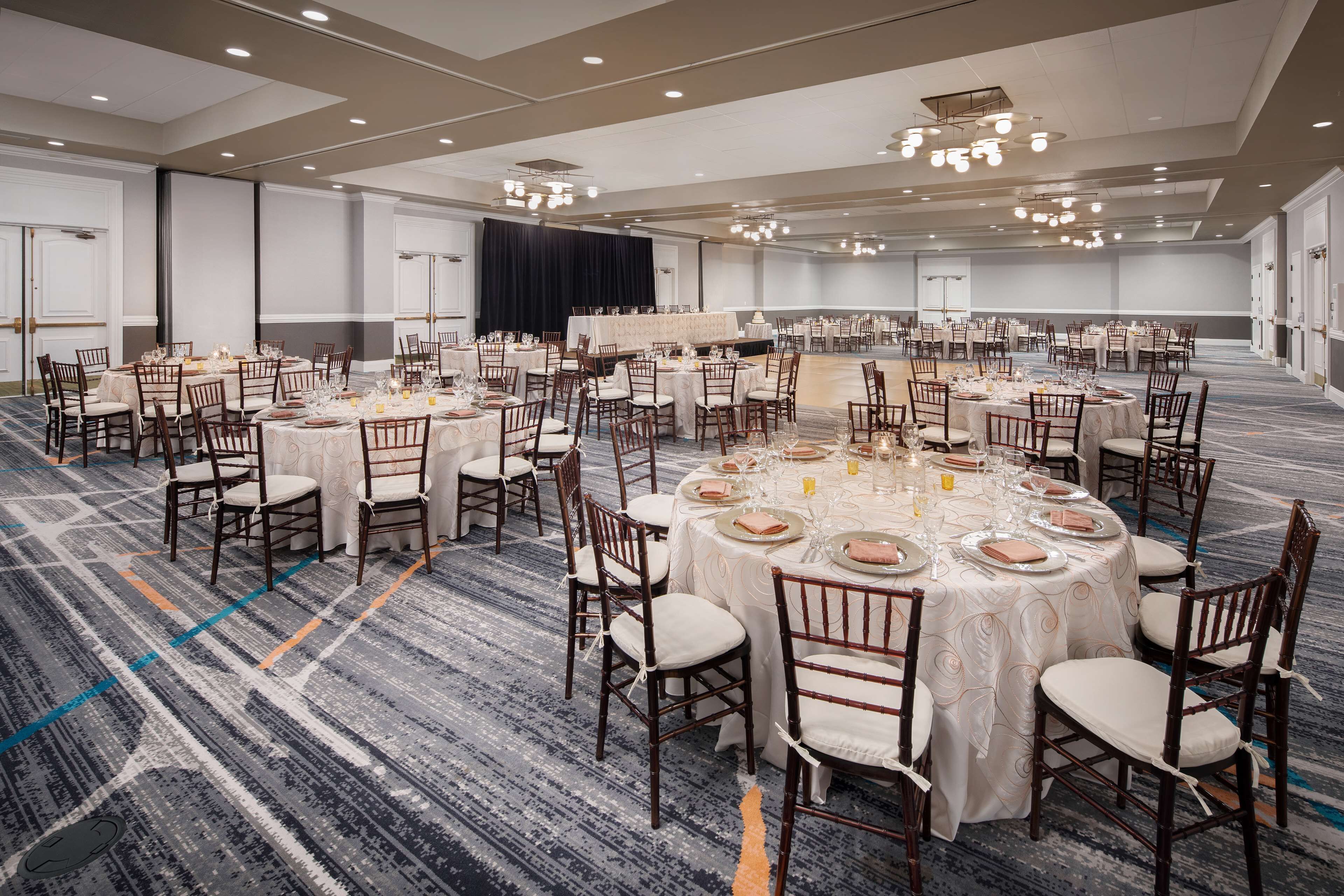 A large banquet hall with round tables set for dining, equipped with chairs and table settings.