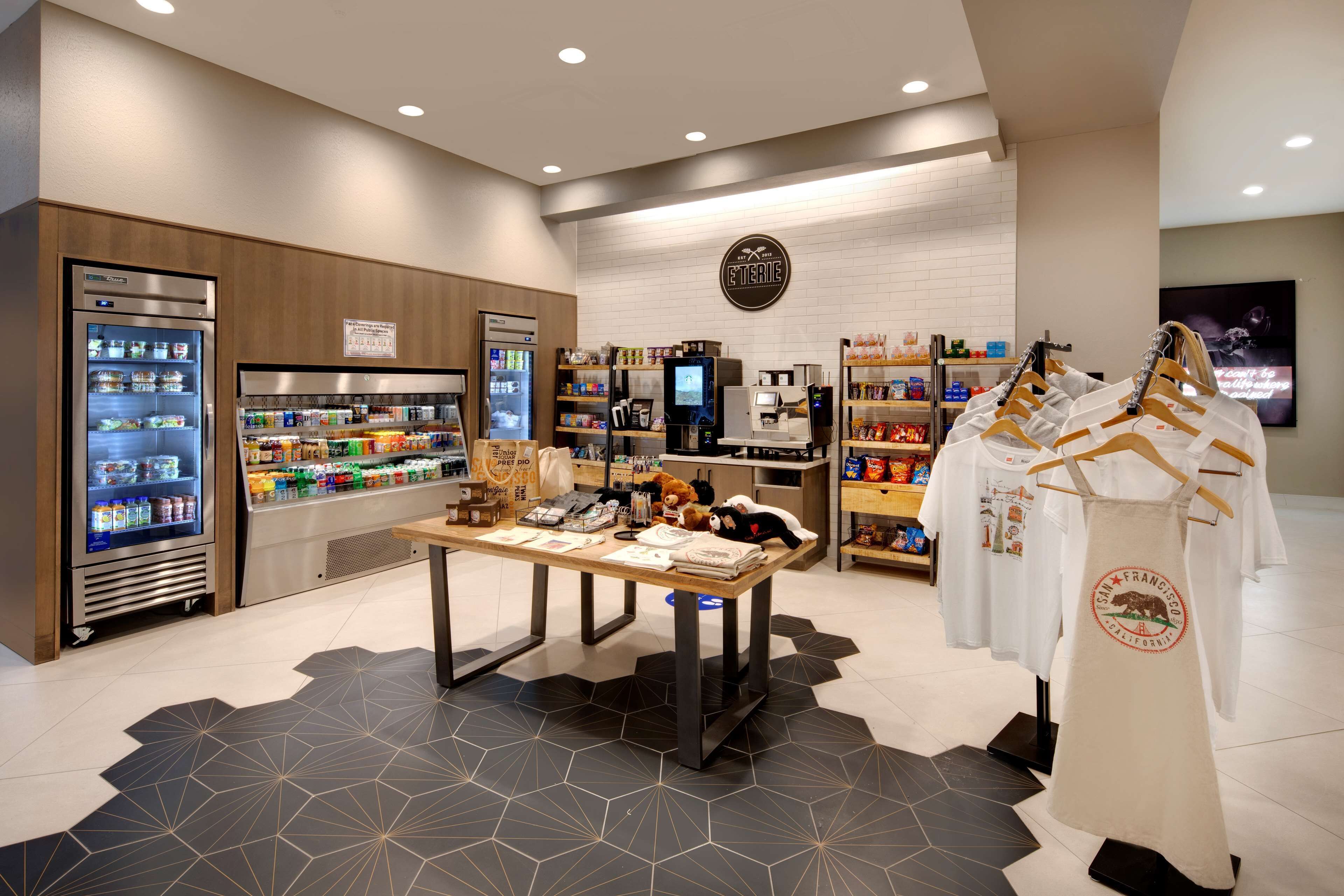 A modern retail space with refrigerated display cases, a checkout counter, and a variety of products on shelves.