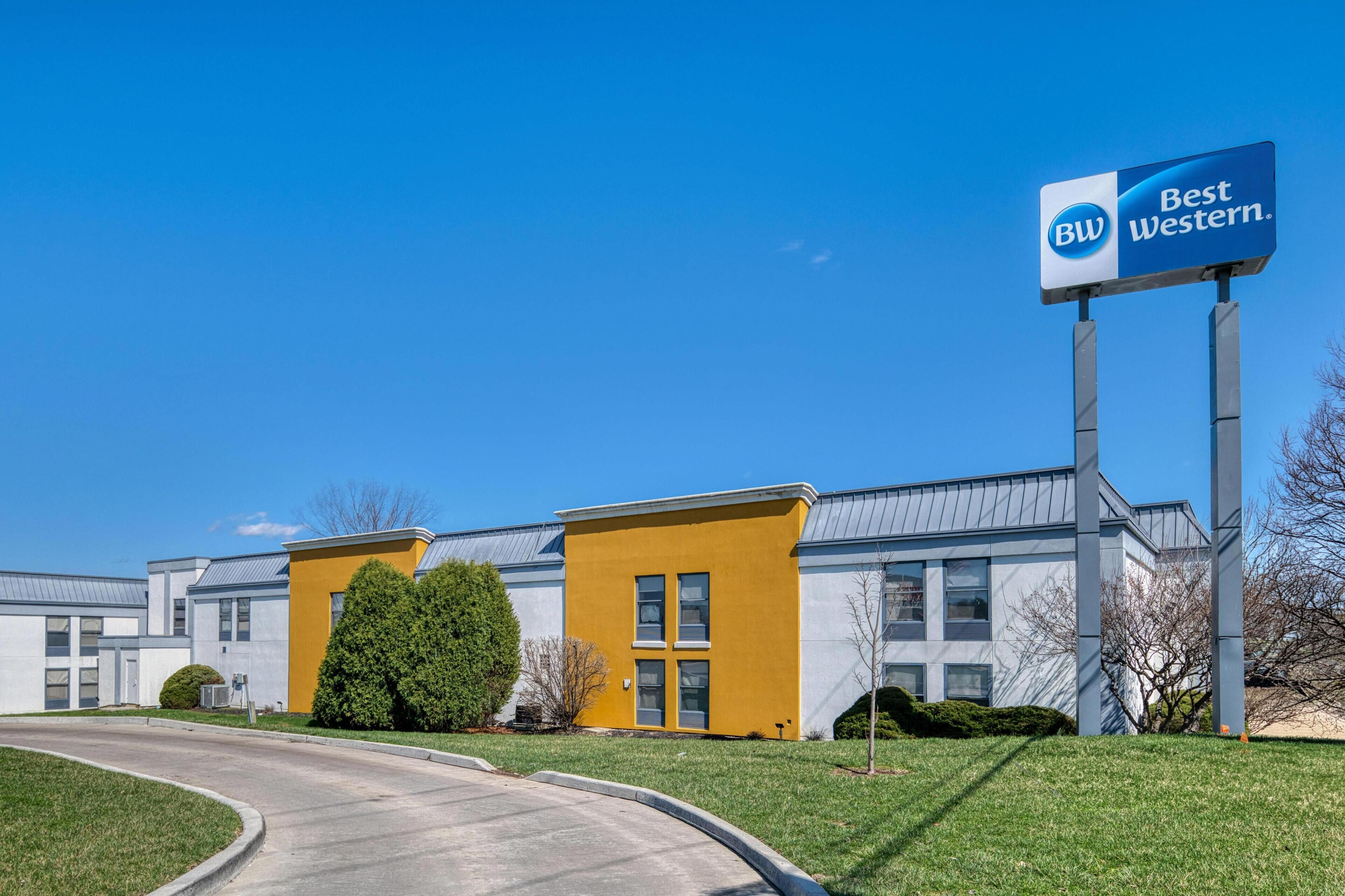 A Best Western hotel with a modern design, featuring a yellow accent wall and a clear blue sky.