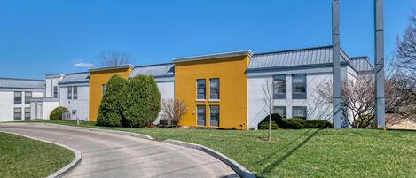 A Best Western hotel with a modern design, featuring a yellow accent wall and a clear blue sky.