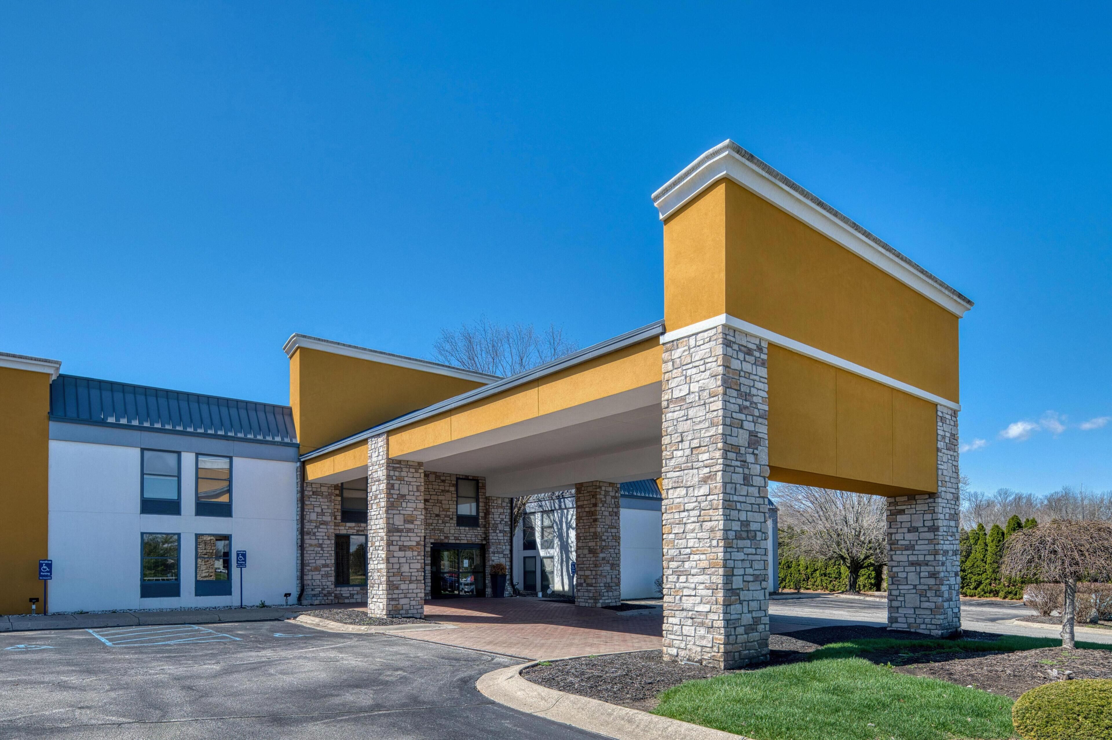 A building with a yellow facade, stone pillars, and a covered entrance.