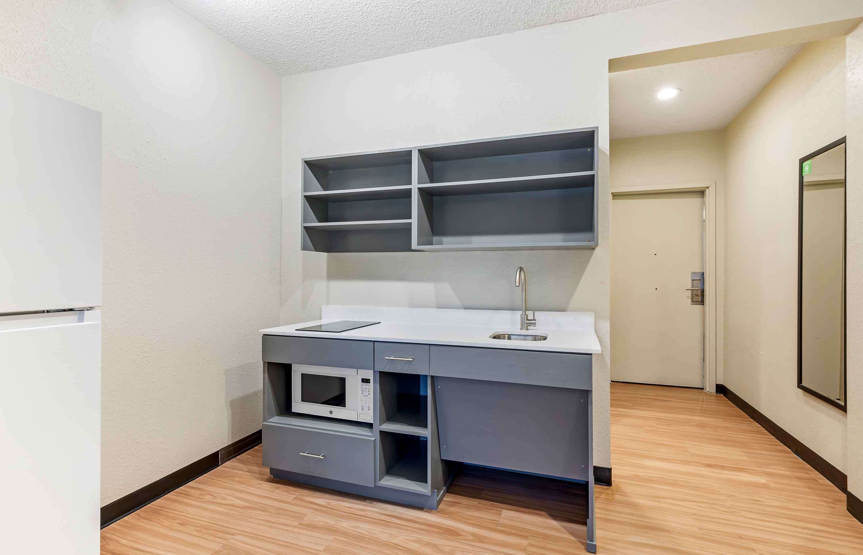 A compact kitchen with a built-in microwave, a sink, and a countertop with storage drawers.