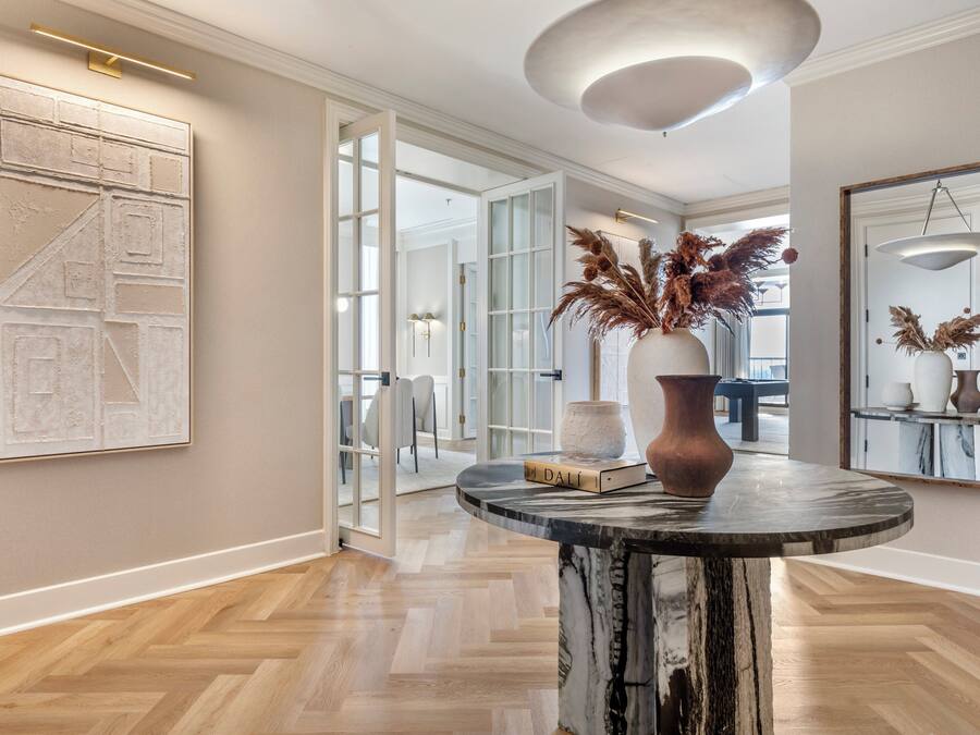 Un intérieur moderne avec une table en marbre, un grand tableau abstrait et un vase contenant des plantes séchées.