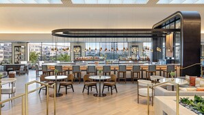 A modern restaurant with a bar area, seating arrangements, and a view of the cityscape. - Omni Las Colinas Hotel (Irving)