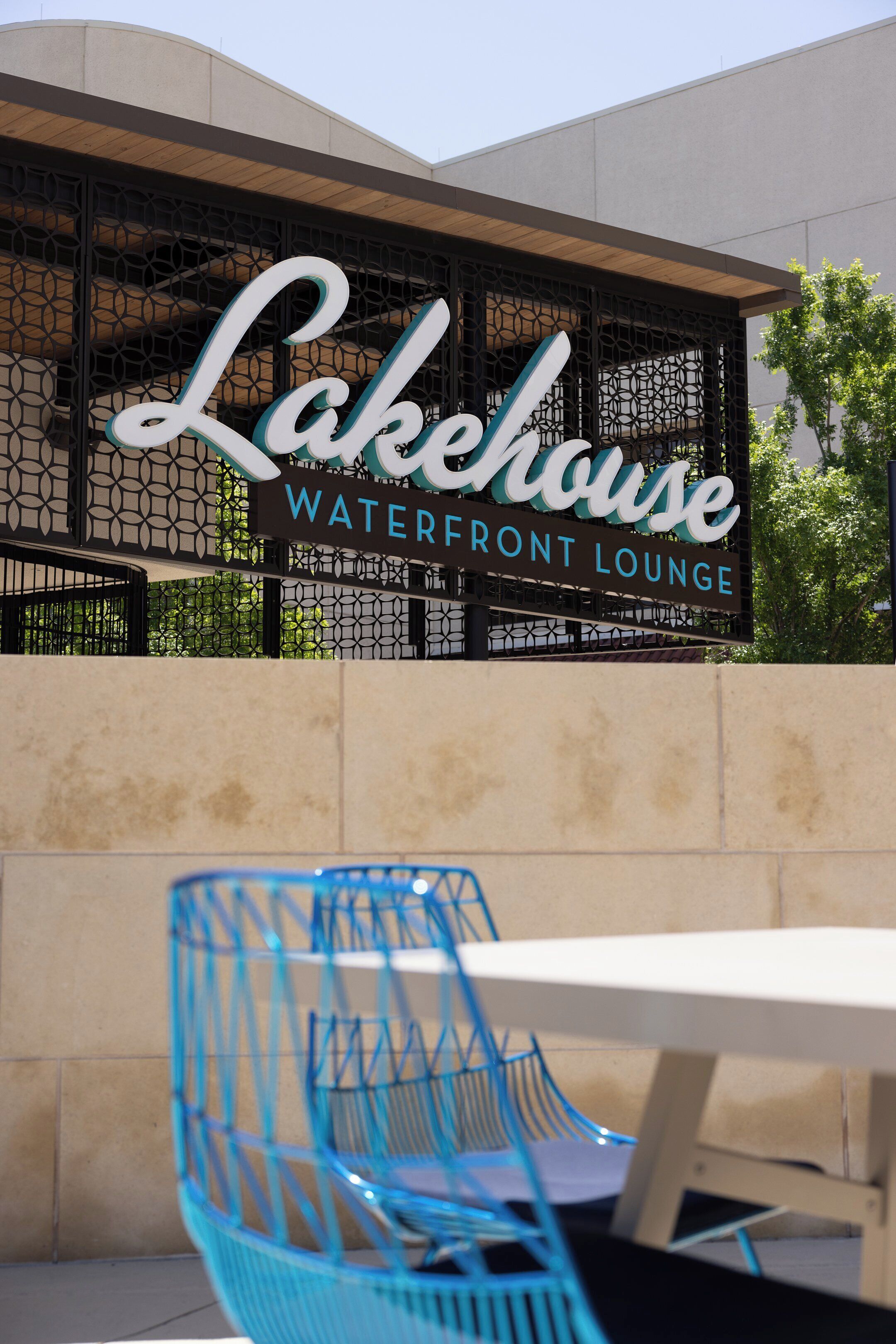 Schild für das Lakehouse Waterfront Lounge, mit modernem Design und Sitzbereich im Freien.