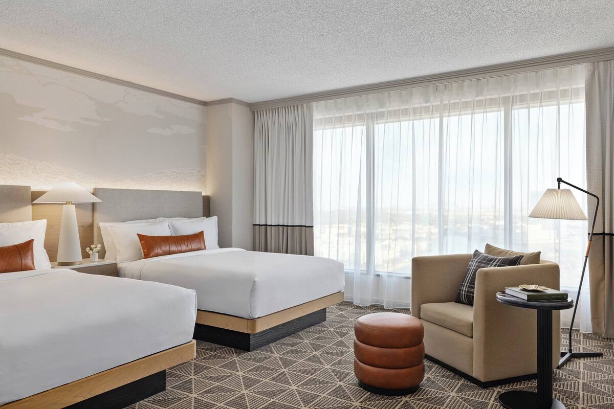 A hotel room with two beds, a sofa, a small table, and a lamp.