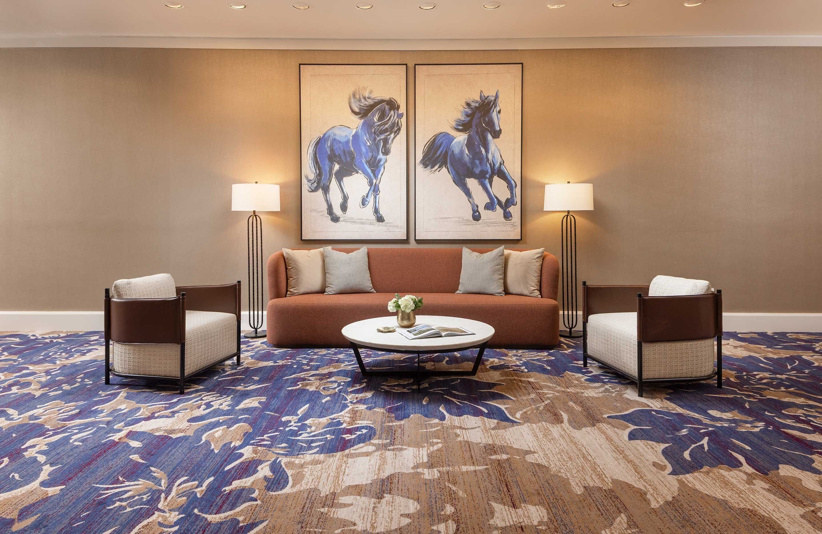A hotel room with a sofa, two armchairs, a coffee table, and two wall-mounted lamps.