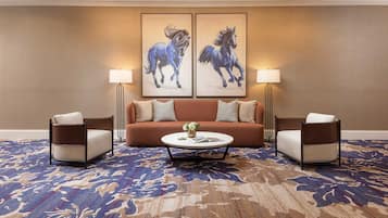 A hotel room with a sofa, two armchairs, a coffee table, and two wall-mounted lamps.