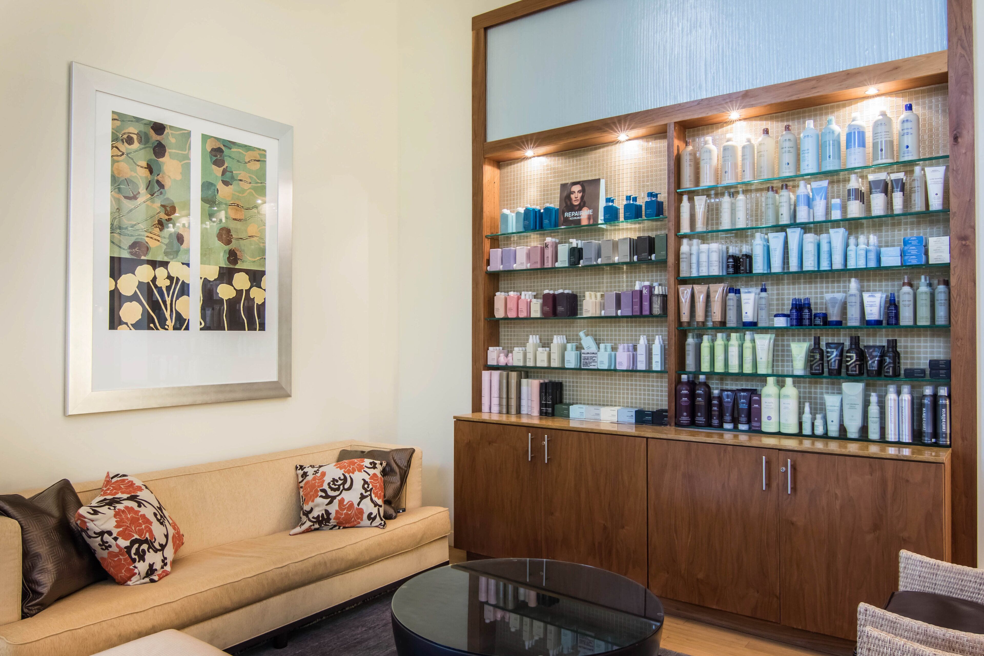 A reception area with a sofa, a glass display cabinet with various products, and a framed artwork on the wall.