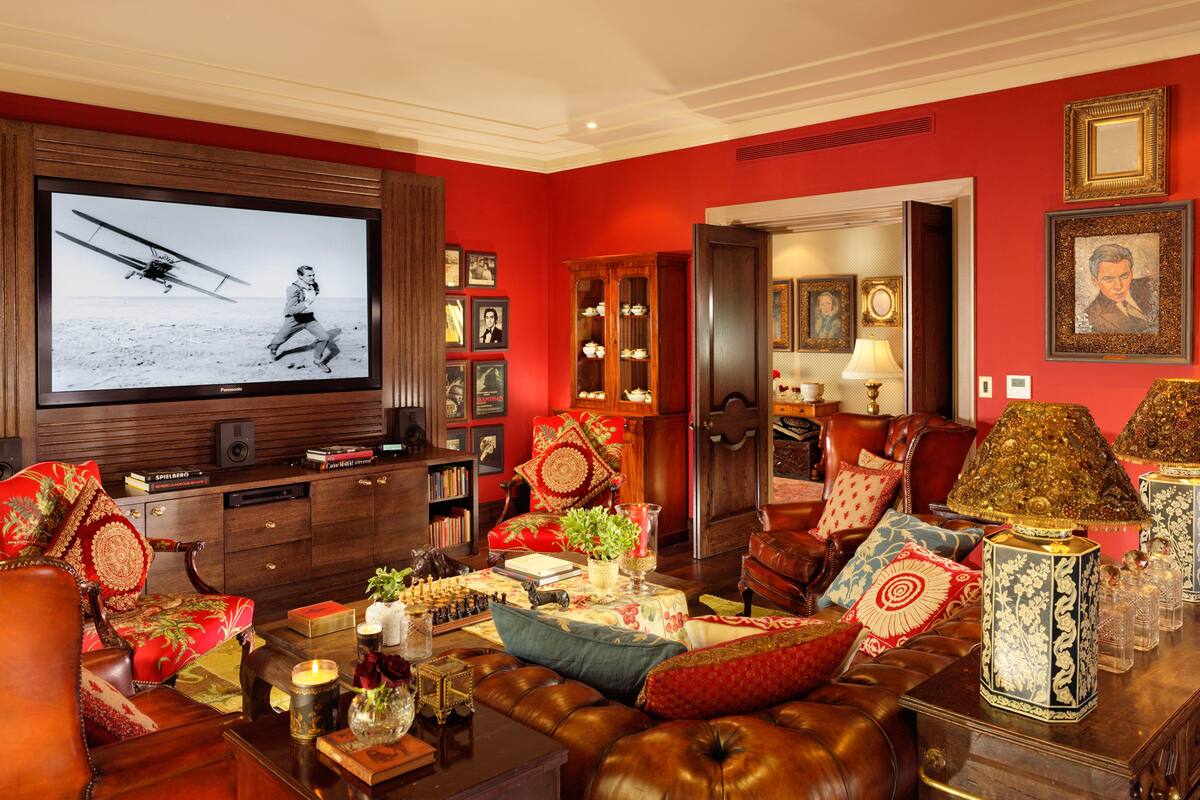 Un salon doté d’un grand téléviseur à écran plat, de canapés en cuir, d’une table basse agrémentée d’objets décoratifs et d’une bibliothèque remplie de livres et de photos encadrées.