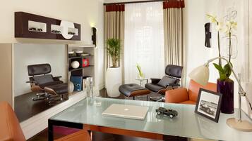 A modern living room with a glass coffee table, leather sofas, a laptop, and a bookshelf with decorative items.