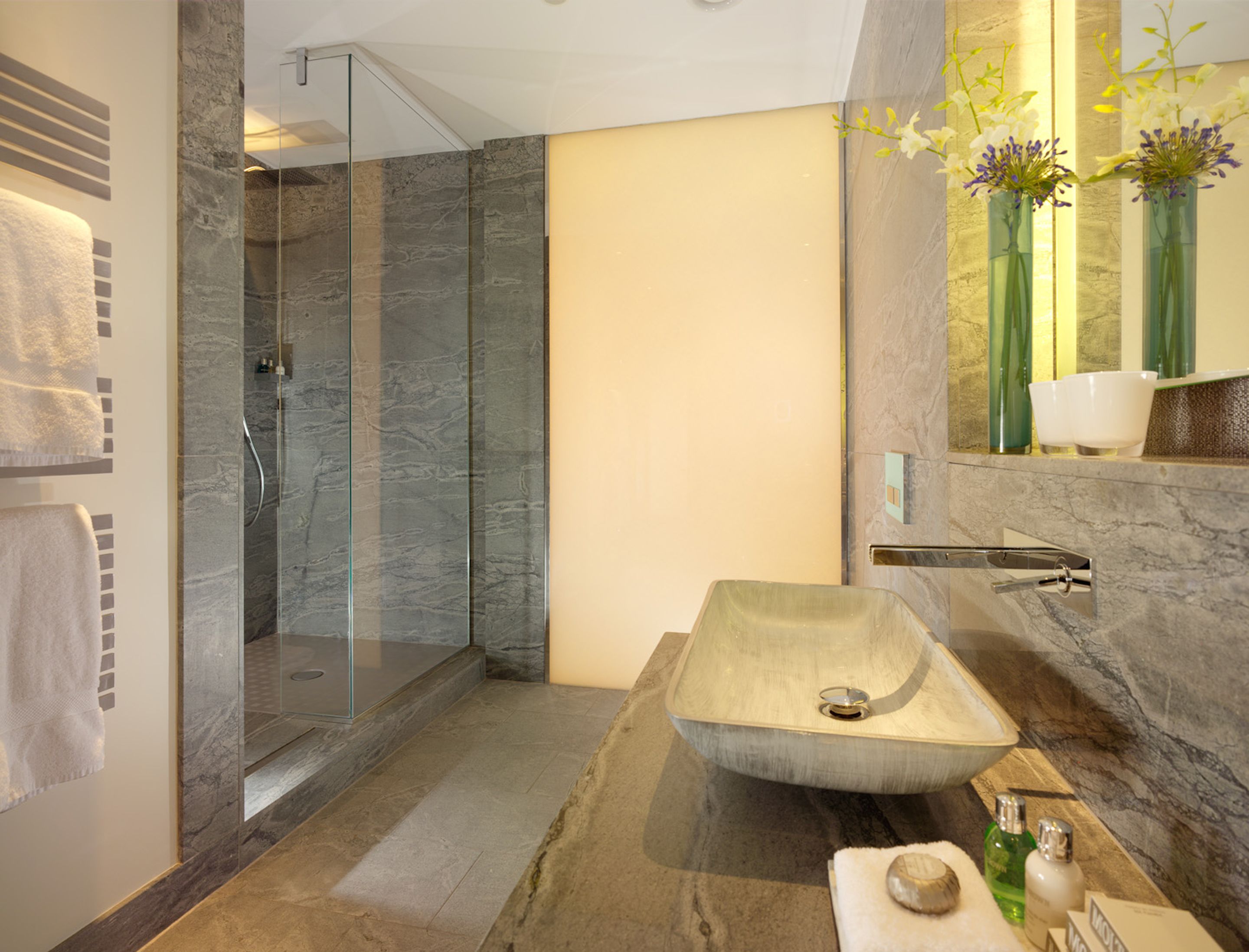 Un bany modern amb un gran lavabo rectangular, una dutxa envidriada i un tocador amb superfície de marbre.