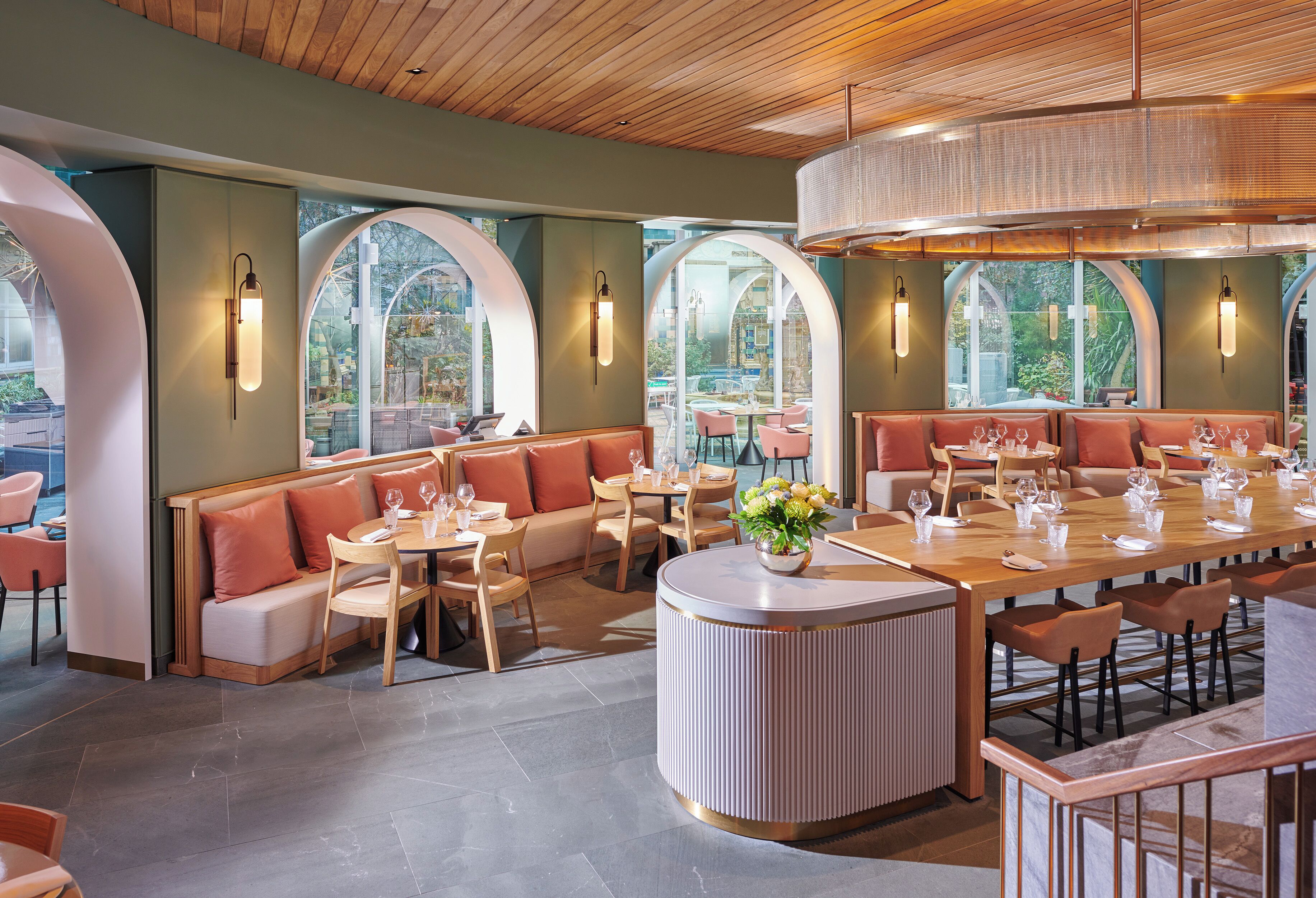 A modern restaurant with round tables, cushioned seating, and large windows.