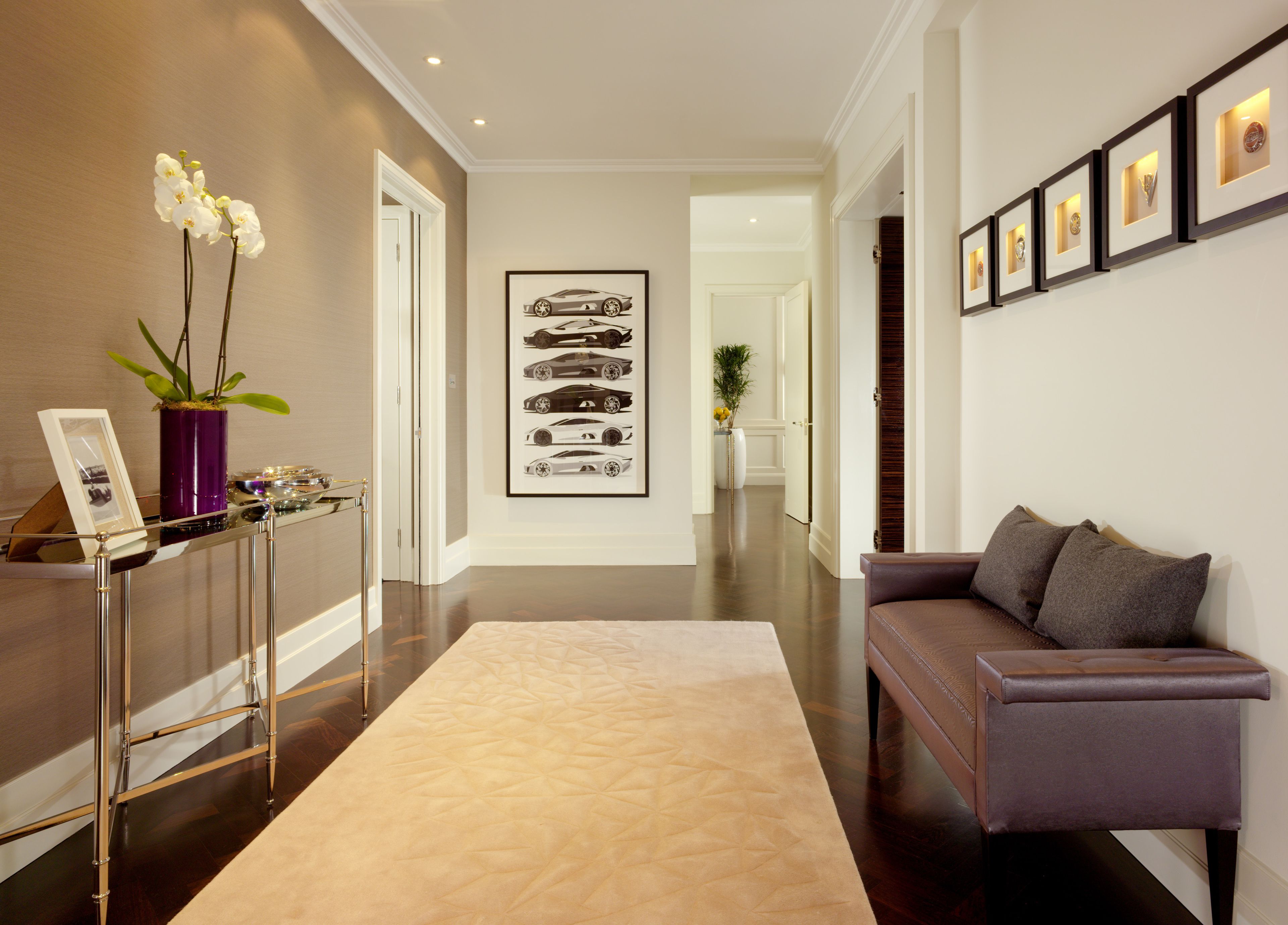 A modern hallway with a sofa, a display of framed items, and a plant.