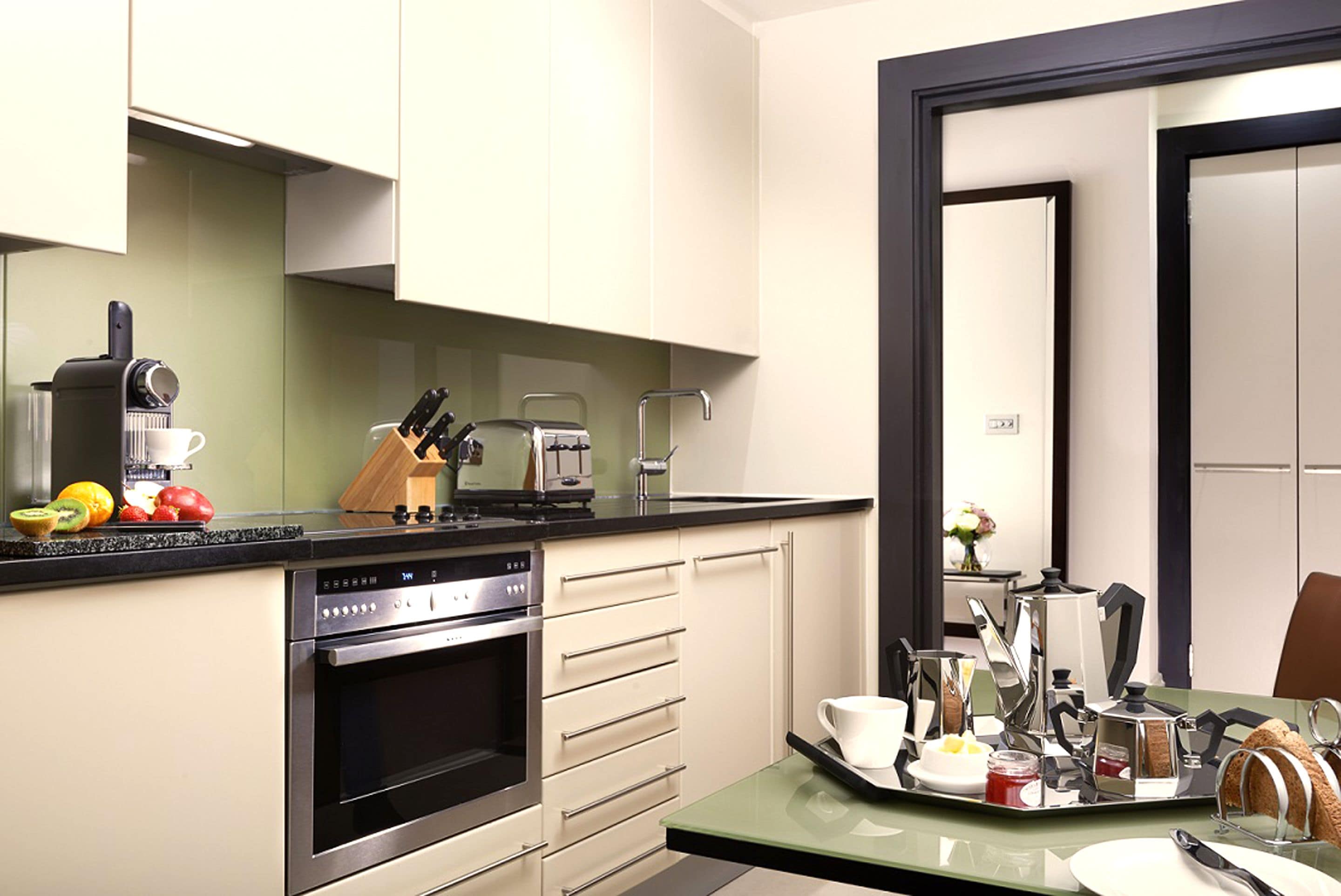 A modern kitchen with a built-in oven, a coffee maker, and a fruit bowl.