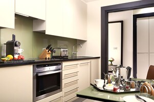 A modern kitchen with a built-in oven, a coffee maker, and a fruit bowl.