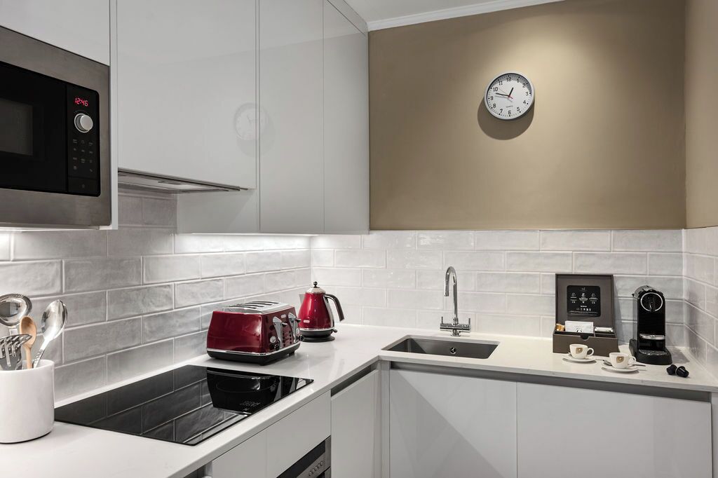 A modern kitchen with a microwave, toaster, kettle, sink, and coffee maker.