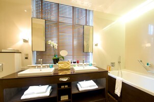 A bathroom with two sinks, a large mirror, and a bathtub.