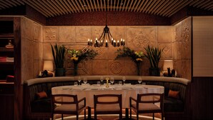A round dining table set for four with a chandelier above, surrounded by cushioned seating. - Taj 51 Buckingham Gate, Suites and Residences (London)