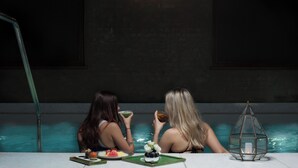 Two individuals in a dimly lit indoor pool area with a ladder, a decorative lantern, and a table with food and drinks. - Taj 51 Buckingham Gate, Suites and Residences (London)