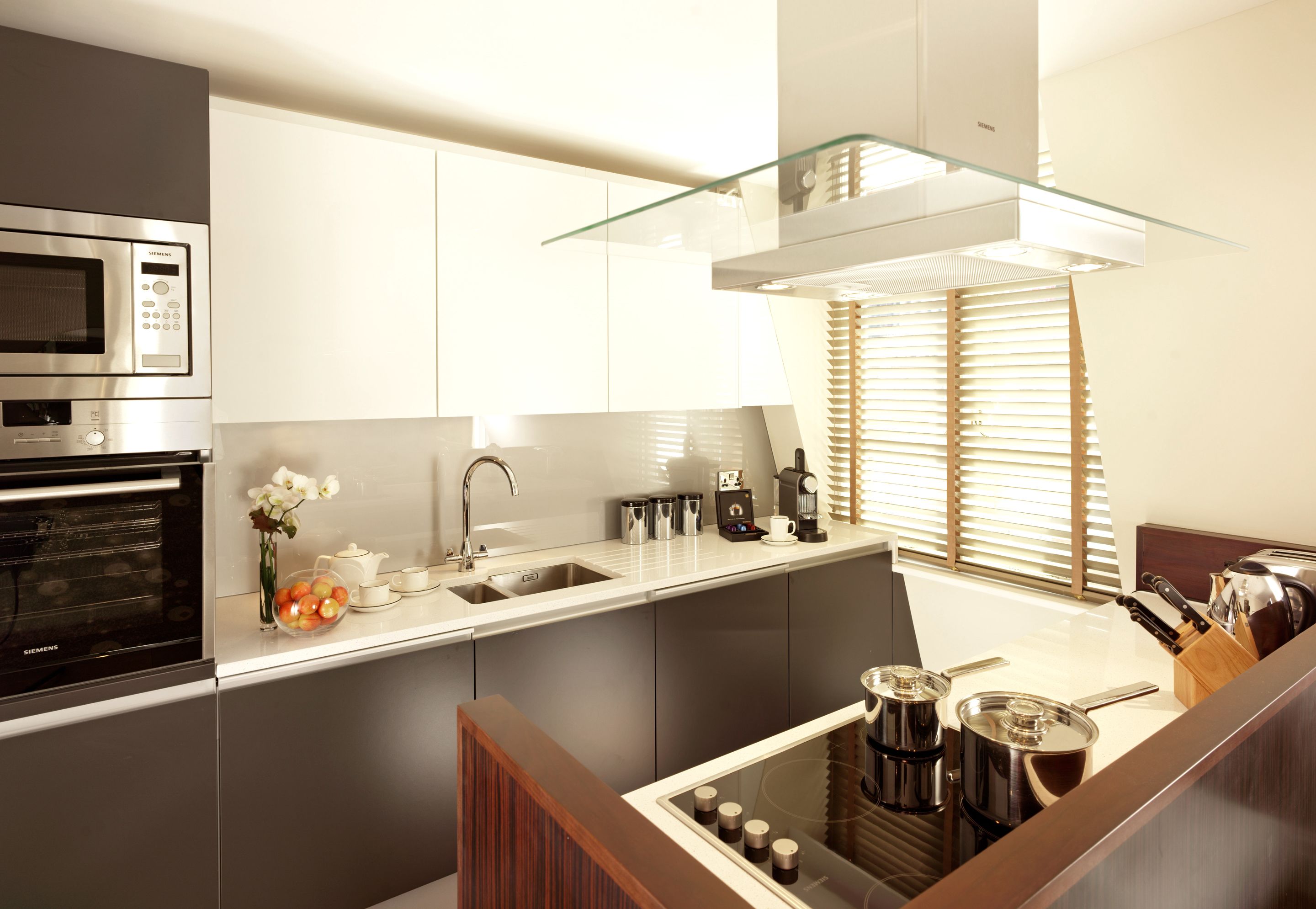 Una cucina moderna con forno integrato, ripiano in vetro e macchina per il caffè.