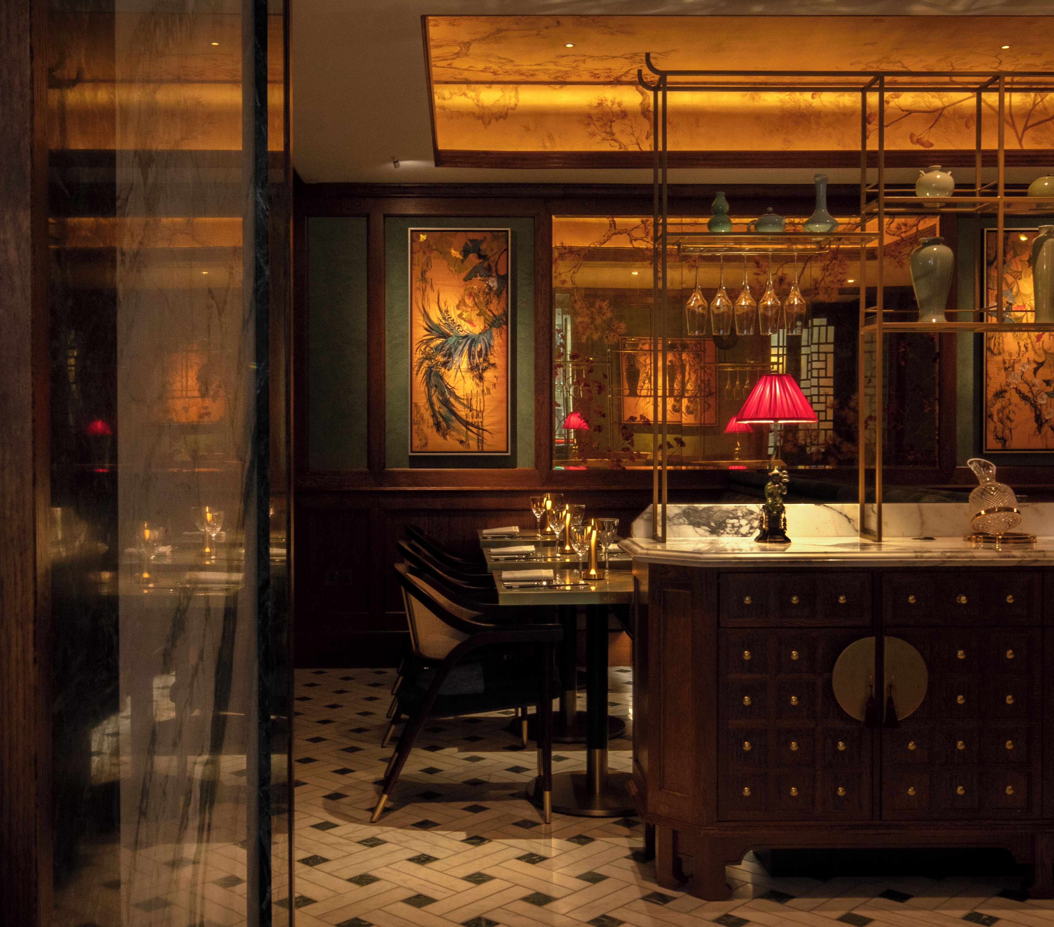 A dimly lit bar area with a wooden bar counter, hanging light fixtures, and a dining table with chairs.