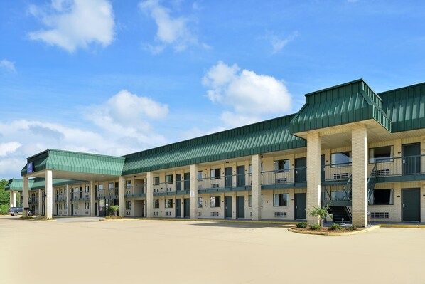 A multi-story motel with a green roof and white brick exterior.