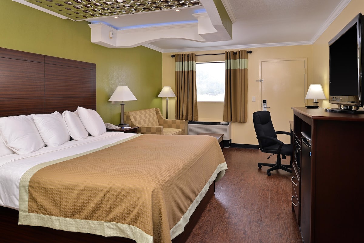 Habitación de hotel con una cama grande, un escritorio con computadora, una silla y televisión.