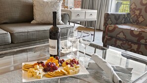 A glass-top table with a wine bottle, two glasses, and a cheese board with crackers and grapes. - Turf Valley Resort (Ellicott City)