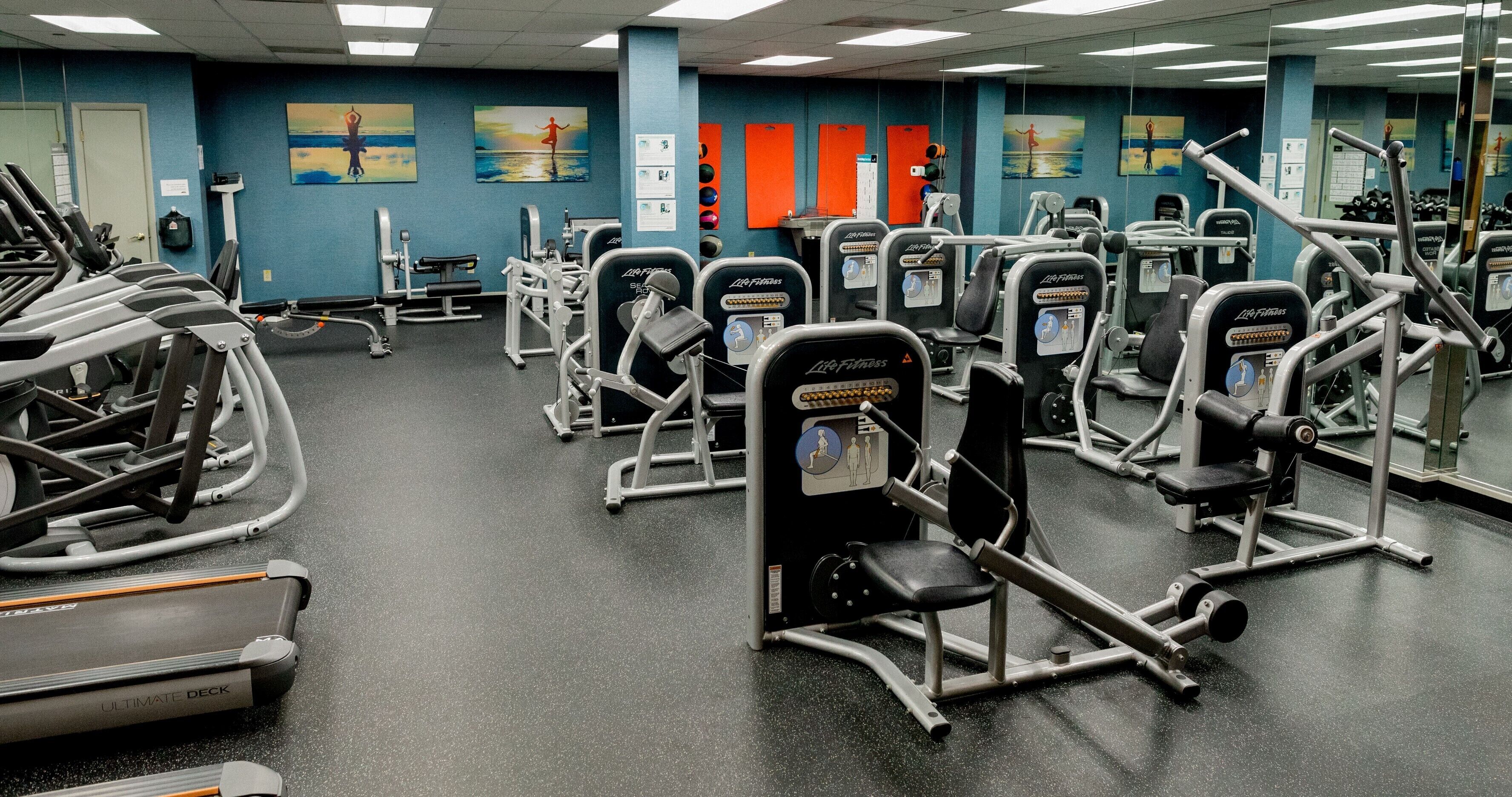 A gym with cardio equipment, weight machines, and mirrors.
