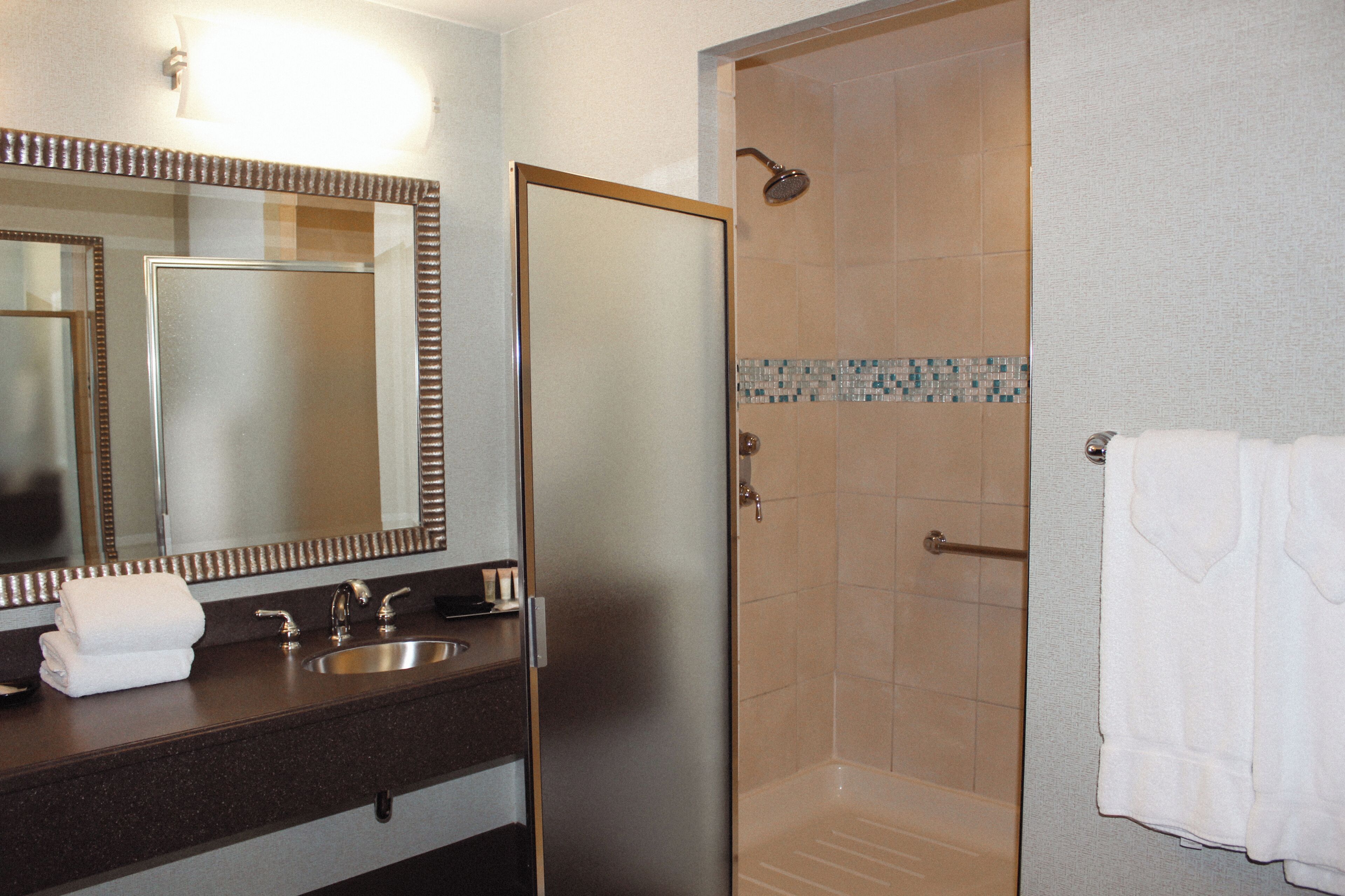 Un baño con lavamanos, espejo y cabina de ducha.