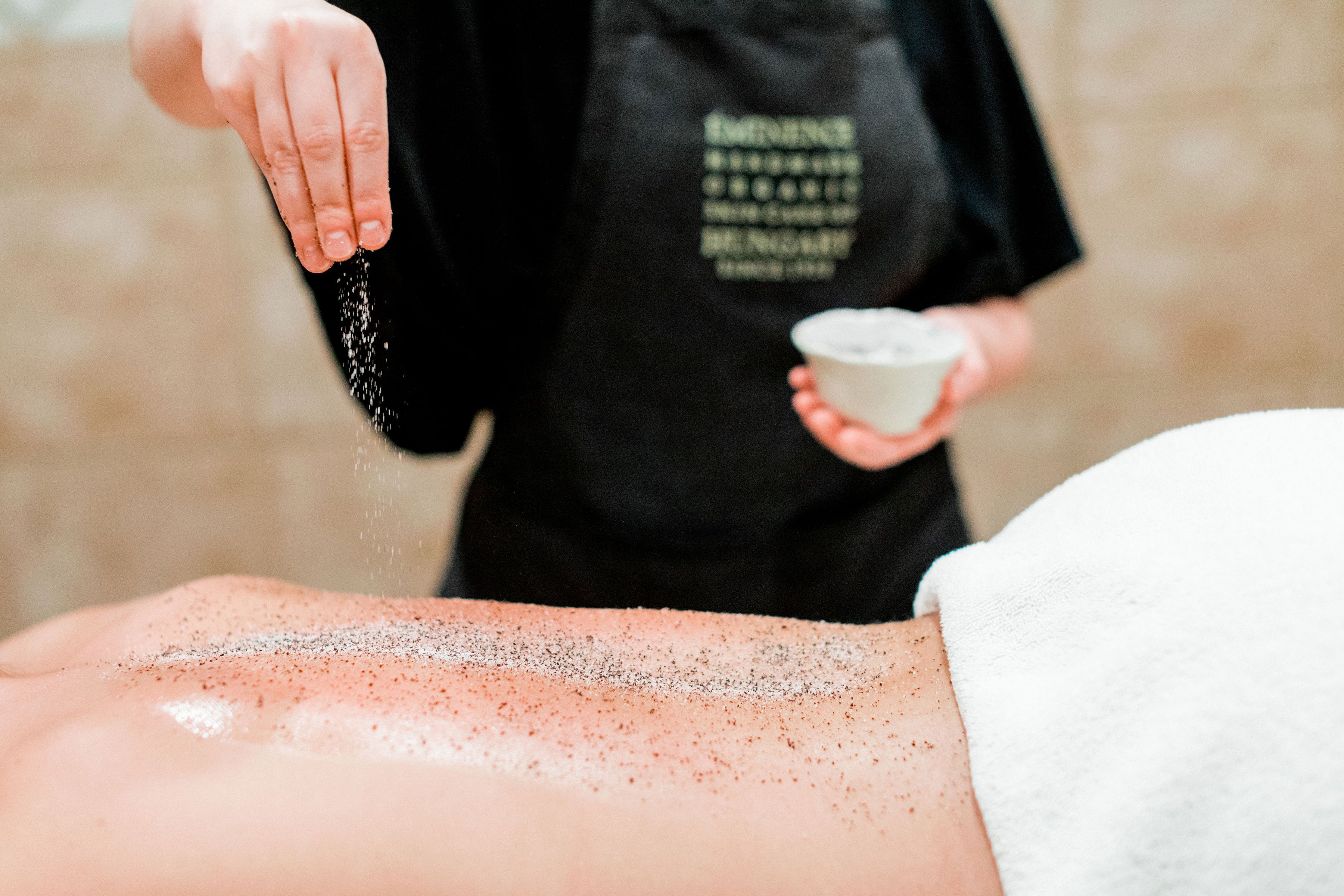 A person receiving a facial treatment with a powder being sprinkled on their face.